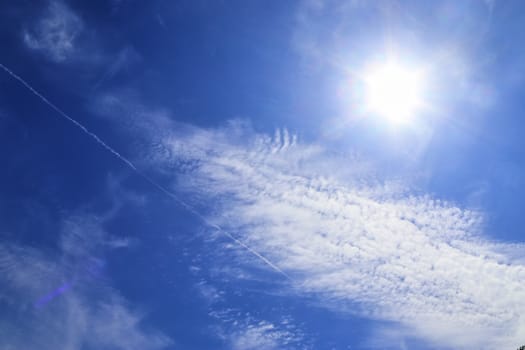 Beautiful view at bright sunbeams with some lens flares and clouds in a blue sky