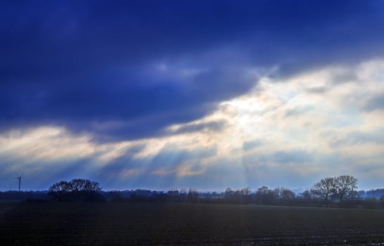 Beautiful view at bright sunbeams with some lens flares and clouds in a blue sky