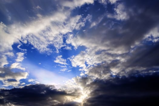 Beautiful view at bright sunbeams with some lens flares and clouds in a blue sky