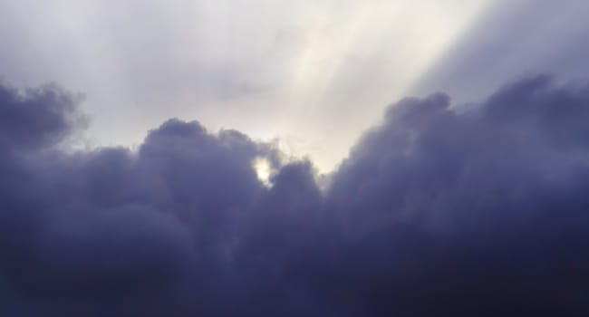 Beautiful view at bright sunbeams with some lens flares and clouds in a blue sky