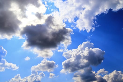 Beautiful view at bright sunbeams with some lens flares and clouds in a blue sky