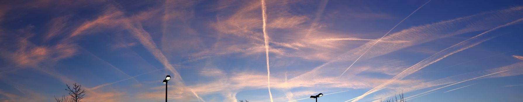 Aircraft condensation contrails in the blue sky inbetween some beautiful clouds