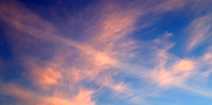 Aircraft condensation contrails in the blue sky inbetween some beautiful clouds