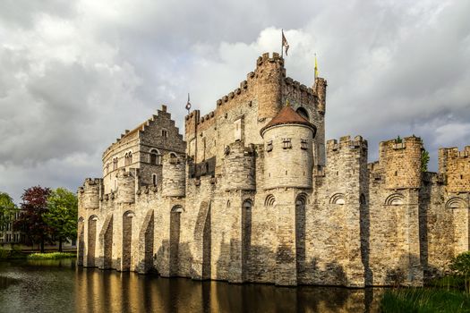 Fortified walls and towers of Gravensteen medieval castle with moat in the foreground, Ghent East Flanders, Belgium