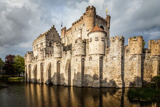 Fortified walls and towers of Gravensteen medieval castle with moat in the foreground, Ghent East Flanders, Belgium