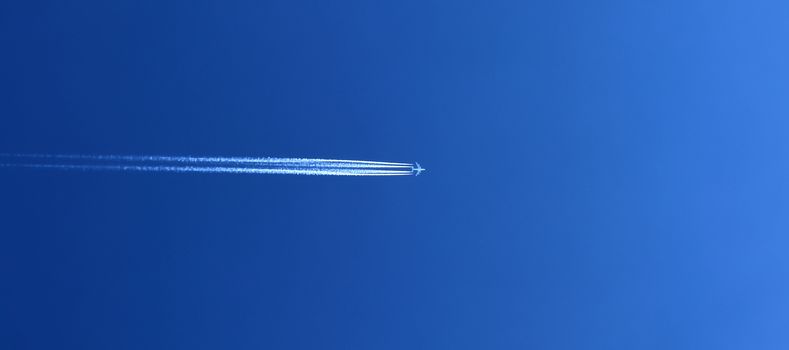 Aircraft condensation contrails in the blue sky inbetween some beautiful clouds