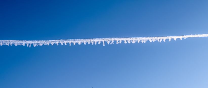 Aircraft condensation contrails in the blue sky inbetween some beautiful clouds