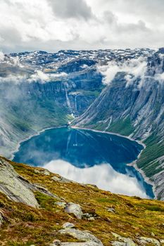 Blue lake surrounded by steep cliffs hiding in clouds, Odda, Hordaland county, Norway