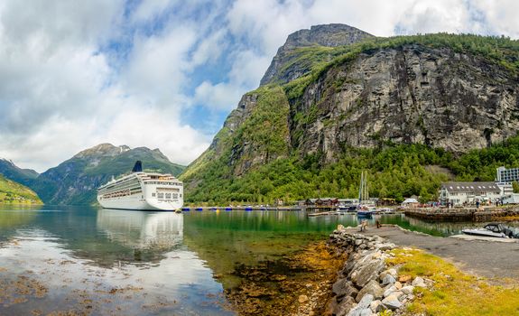 Cruise liner anchored in the port of Geiranger village with fjord landscape in the background, Sunnmore,  Romsdal county, western Norway