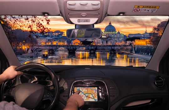 Driving a car while using the touch screen of a GPS navigation system towards Saint Peter's Church during a wonderful sunset in Rome, Italy