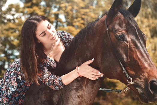 Pretty Hispanic brunette giving her horse a hug while riding him in the forest