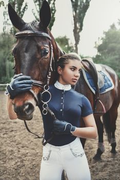 Posing for the camera. Happy woman with her horse on the ranch at daytime.