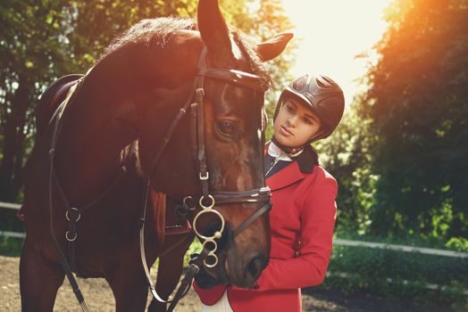 A young girl talking and takes care of her horse. She loves the animals and joyfully spends her time in their environment.