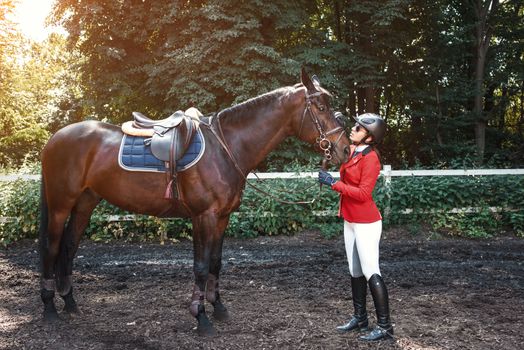 A young girl talking and takes care of her horse. She loves the animals and joyfully spends her time in their environment.