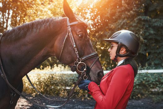 A young girl talking and kissing her horse. She loves the animals and joyfully spends her time in their environment.