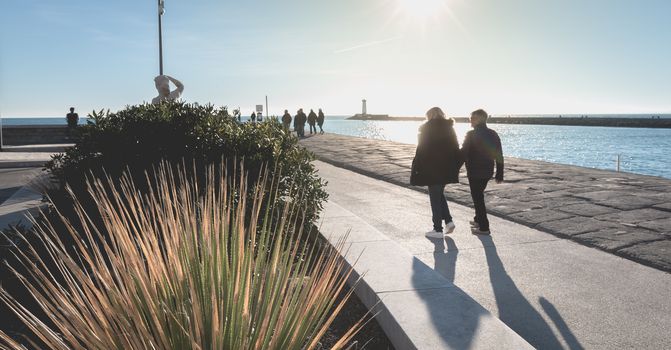 Agde, France - January 01, 2019: street atmosphere of the quays of the port of Agde where people are walking on a winter day