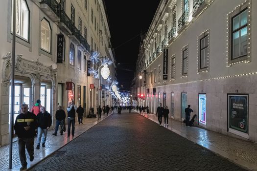 Lisbon, Portugal - November 27, 2018: Street atmosphere in the city center at night decorated for Christmas where people are walking on an autumn evening