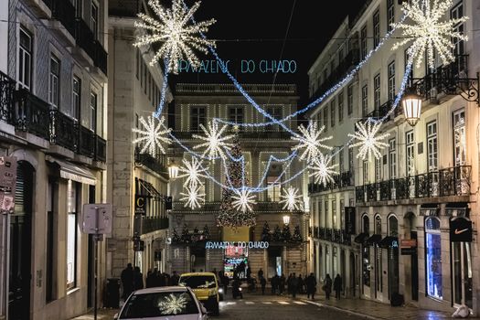 Lisbon, Portugal - November 27, 2018: Street atmosphere in the city center at night decorated for Christmas where people are walking on an autumn evening