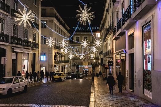 Lisbon, Portugal - November 27, 2018: Street atmosphere in the city center at night decorated for Christmas where people are walking on an autumn evening