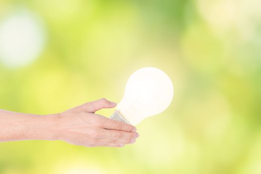 Human hand concept, saving energy from light bulbs, natural bokeh background