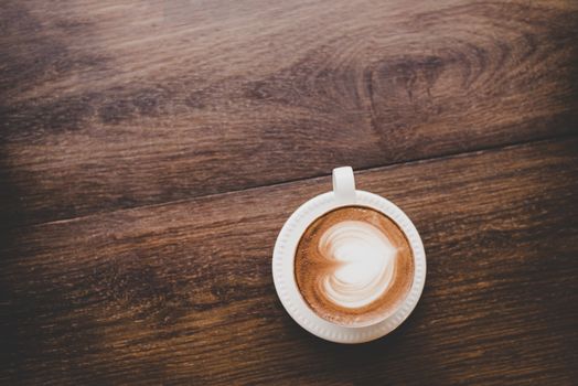 Top view of vintage latte art coffee with heart shape on wooden table.