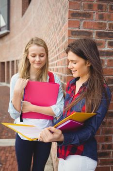 Smiling students reading book at university 