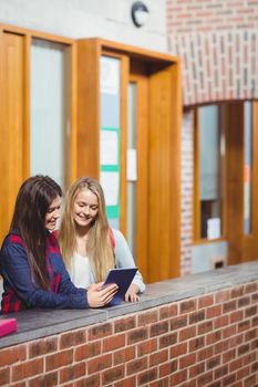 Smiling students using tablet together at university 