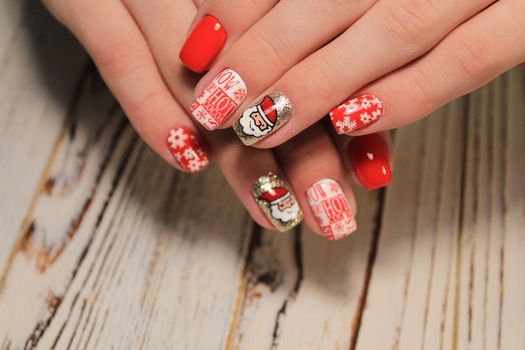 Christmas Nail art manicure. Winter Holiday style bright Manicure with gems Christmas tree and snowflakes. Bottle of Nail Polish.