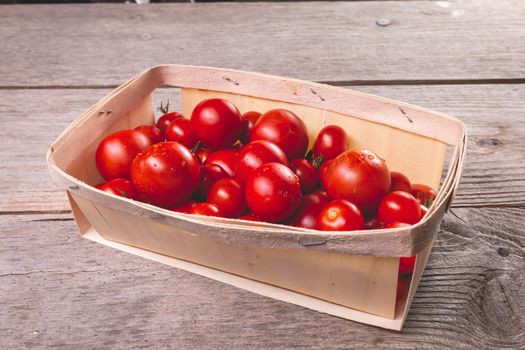 ripe tomatoes in a small wooden crate in studio