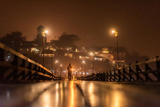 Beautiful night time of silhouette traveler walking on the Mon wooden bridge with beautiful reflections of Sangkhlaburi, Kanchanaburi, Thailand