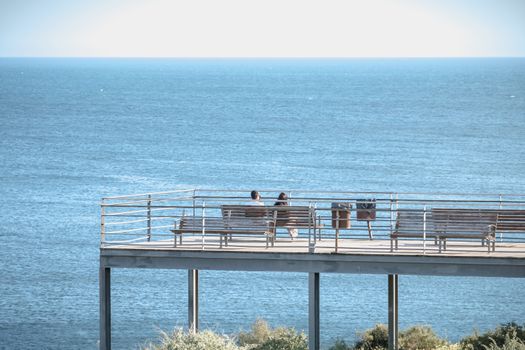 Albufeira, Portugal - May 3, 2018: People enjoying the sea view from the pontoon of a restaurant overlooking the beaches on a spring day