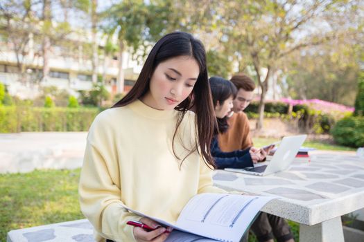 Asian students use notebook computers and tablet to work and study online in garden at home during the coronavirus epidemic and quarantine at home