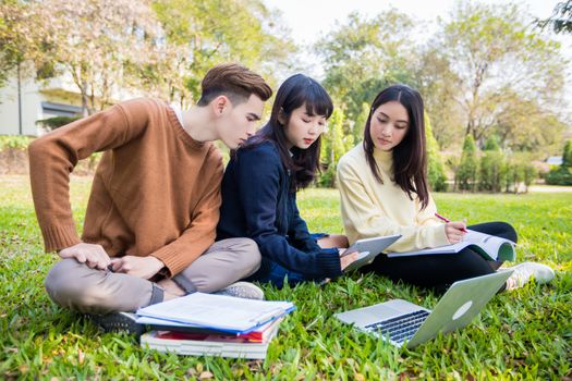 Asian students use notebook computers and tablet to work and study online in garden at home during the coronavirus epidemic and quarantine at home