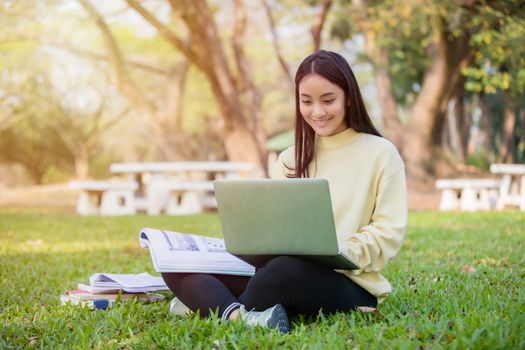 Asian students use notebook computers and tablet to work and study online in garden at home during the coronavirus epidemic and quarantine at home