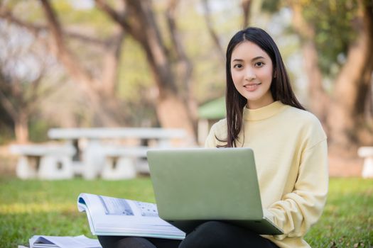 Asian students use notebook computers and tablet to work and study online in garden at home during the coronavirus epidemic and quarantine at home