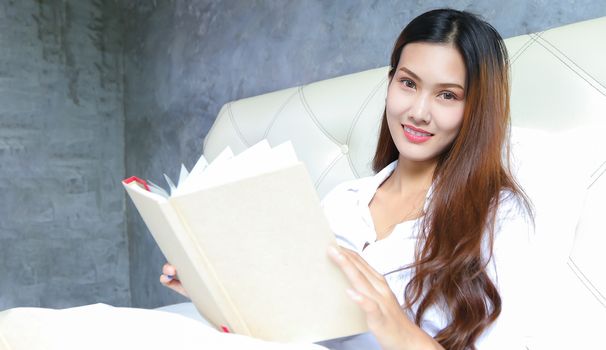 Asian woman reads her bed in the morning at home on a relaxing day.
