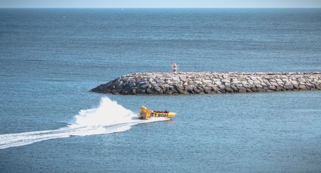 Albufeira, Portugal - May 3, 2018: Jetboat for tourists entering the harbor at full speed on a spring day