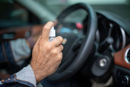 Asian man using spray alcohol to clean the car for coronavirus protection