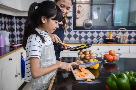 Asian families are cooking  and parents are teaching their daughters to cook in the kitchen at home. 
Family activities on holidays and Happy in recreation concept