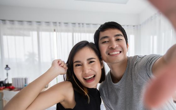 Asian couple lovers lying on their play mobile phones and selfie on bed  at home