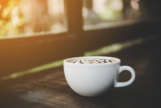 A cup of coffee on wooden table in cafe.