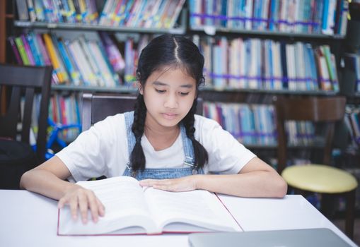 Asian girl students reading books and using notebook in the library.