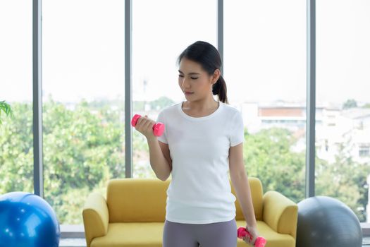 Asian woman exercising with dumbbell at home  