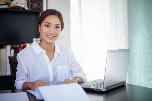 Beautiful Asian business women checking document and using notebook working from home for social distance and self responsibility concept