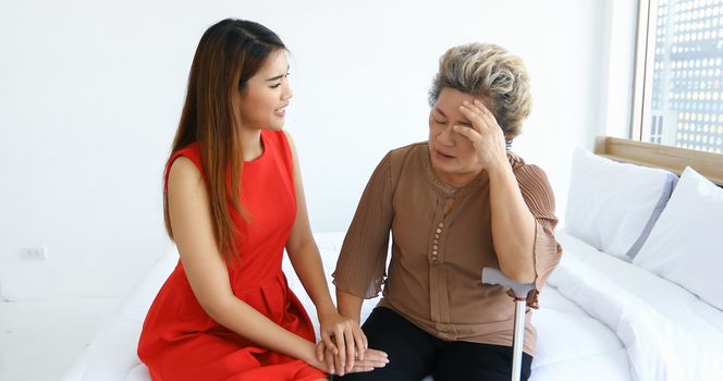 Cheerful  asian woman taking care of her grandmother in bed room at home
