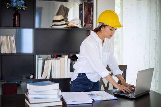 Beautiful Asian engineering women checking document and using notebook working from home for social distance and self responsibility concept