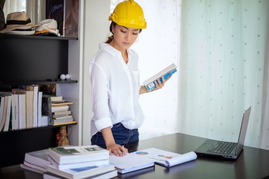Beautiful Asian engineering women checking document and using notebook working from home for social distance and self responsibility concept