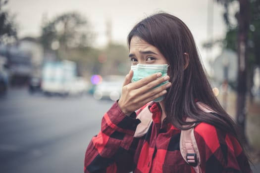 Asian Young woman walking in the city wearing face mask because of air pollution, particulates and for protection flu virus, influenza, coronavirus