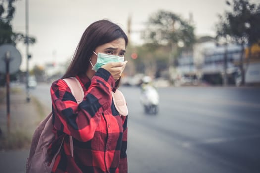 Asian Young woman walking in the city wearing face mask because of air pollution, particulates and for protection flu virus, influenza, coronavirus