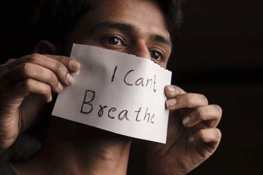 Man covered his face with text I cant breathe in Dark background - concept of protest against the racial discrimination